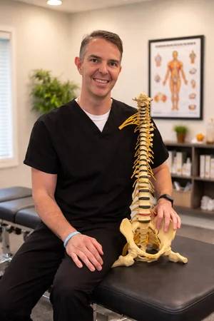 Dr. Ralph S. Cardin holding a spine model in a wellness clinic.