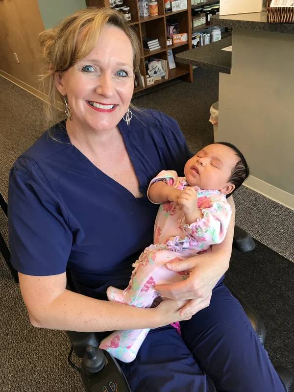Dr. Heather L. Cardin holding a baby in a wellness clinic.